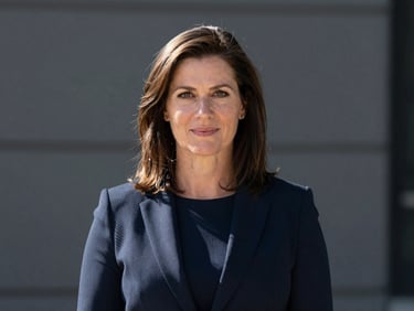 Professional portrait of Jane Smith, crisp corporate photography, sharp natural daylight, deep navy and slate tones, high contrast, professional editorial style.
