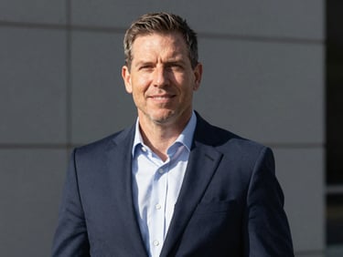 Professional portrait of Mark Johnson, crisp corporate photography, sharp natural daylight, deep navy and slate tones, high contrast, professional editorial style.