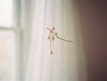 Romantic editorial photography, soft diffused window light, delicate bridal hairpin with subtle pearl details, soft focus background, muted cream and dusty rose tones, shallow depth of field, 35mm film.