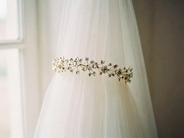 Romantic editorial photography, soft diffused window light, dainty bridal hair adornment with tiny crystals, soft focus background, muted cream and dusty rose tones, shallow depth of field, 35mm film.