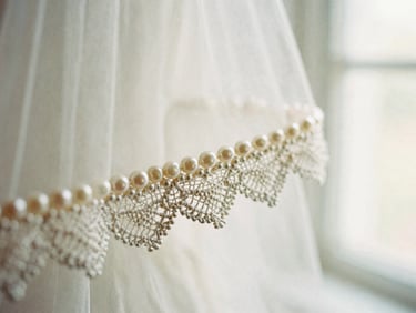 Romantic editorial photography, soft diffused window light, extreme macro close-up of hand-sewn pearls and delicate lace trim on a bridal veil, muted cream and dusty rose tones, shallow depth of field, 35mm film.