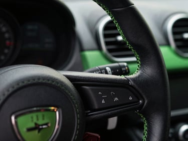 Macro shot of a pristine sports car steering wheel, detailed leather stitching, clean dashboard vents, sharp contrast
