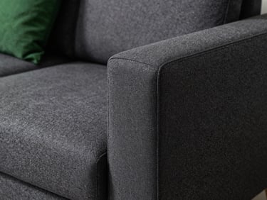 Close-up of a modern dark grey fabric sofa, perfectly clean fibers, crisp natural side lighting, high contrast