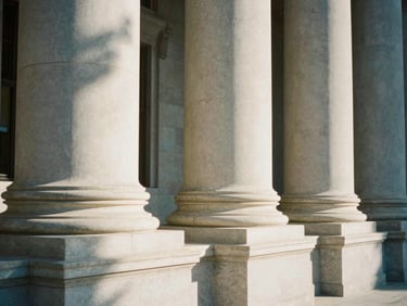 Architectural detail of a federal court building with grand stone pillars, soft natural window light casting long shadows, 35mm