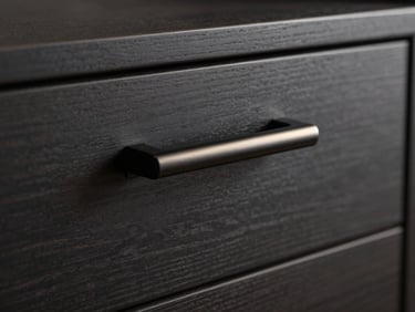 Close-up of a sleek matte black cabinet handle mounted on a dark charcoal timber drawer, moody studio lighting.