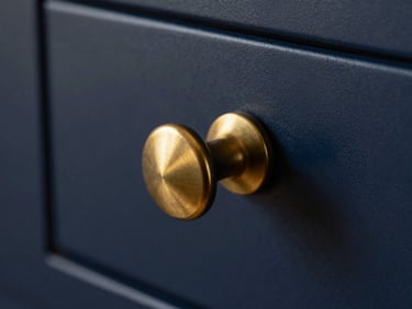 Macro shot of a knurled brass drawer knob on a deep navy cabinet, soft golden hour lighting.
