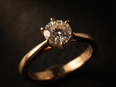 Elegant macro shot of a gold diamond ring catching warm directional studio light, soft golden reflections, dark background, 85mm lens