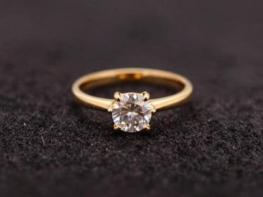 Macro shot of a gold ring with a sparkling clear gemstone on a dark velvet surface, soft focus, warm reflections