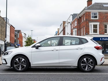 Clean exterior profile of a modern, dual-controlled automatic hatchback on a Birmingham street, bright overcast daylight, authentic UK setting