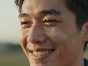 Candid close-up of a man smiling with tears in his eyes, soft natural golden-hour light, warm organic tones, shallow depth of field