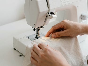 Hands guiding linen fabric through a heavy-duty sewing machine, soft focus, high-contrast rich tones, natural overcast daylight, 35mm