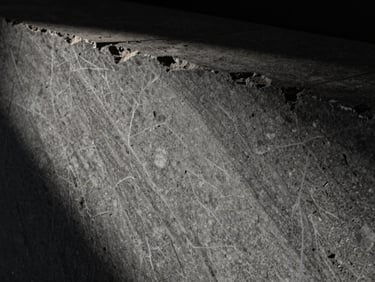 Extreme close-up of deeply veined raw travertine slab, dramatic side-lighting, deep shadows, 35mm lens.