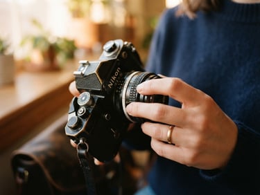 Close-up of a hand adjusting a vintage 35mm camera lens, warm golden-hour window light, shallow depth of field, rich navy tones.