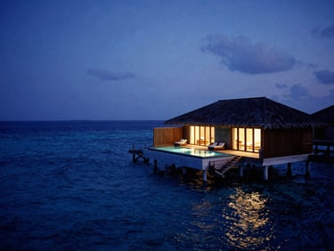 An overwater villa in the Maldives at twilight, glowing private pool, endless deep blue ocean