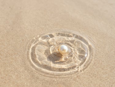 Close-up macro shot of ripples spreading in clear water over light sand, soft morning light, warm editorial photography, 35mm