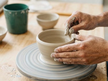 Close up of hands crafting clay pottery on a wooden table, warm golden light, natural textures