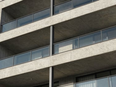 Architectural detail of a modern apartment balcony, concrete and steel construction under crisp daylight.