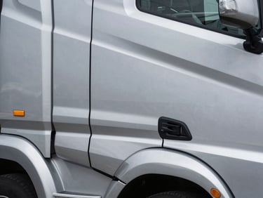 Close-up geometric detail of a modern commercial transport truck, polished steel and clean lines.