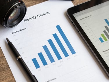 Overhead flat-lay of a desk with printed analytics report, a pen, and a tablet showing a bar chart of monthly revenue growth, even natural light