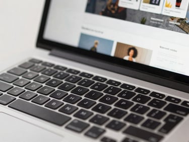 Tight close-up of a laptop keyboard and screen showing a live website homepage with clear navigation, studio lighting, clean and sharp