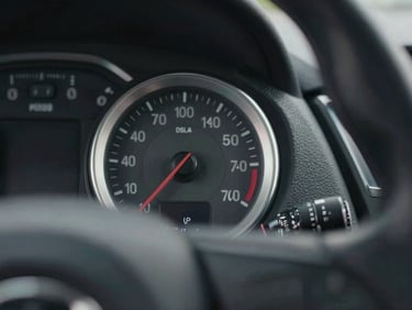 Close-up of a premium machined aluminum dashboard dial and steering wheel texture, moody overcast daylight lighting