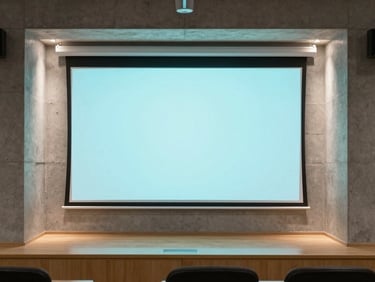 Modern educational space with clean concrete walls, illuminated by a soft cyan digital overlay on a projection screen, architectural framing