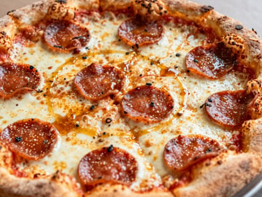 Close-up of a spicy pepperoni pizza with crispy curled edges, bubbling cheese, and a drizzle of hot honey.