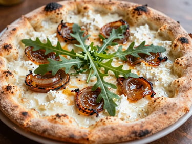 Close-up of a white pizza with creamy goat cheese, caramelized onions, and fresh arugula on a charred crust.