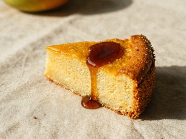 A slice of golden corn cake on a raw linen cloth, warm syrup of dark molasses dripping down the side, low-angle light