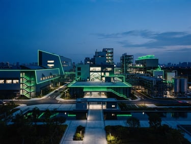 Wide architectural shot of a modern industrial facility at dusk, clean lines, deep blue ambient light with sharp green accents, 35mm photography