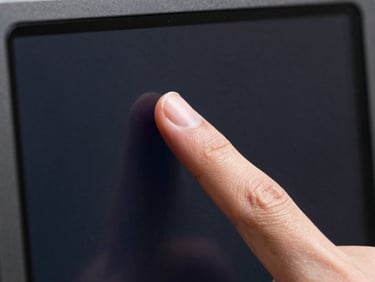 Close-up of fingertip resting on a dark screen showing a frozen animation frame, clean studio strobe, single sharp highlight on the glass surface