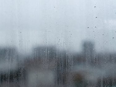 Extreme macro close-up of water sheeting evenly over a coated glass surface, high-contrast cool tones, crisp details, bright direct daylight.