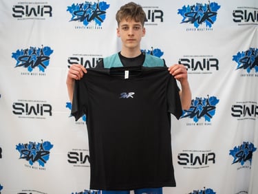 A boy holding a black SWR T-shirt