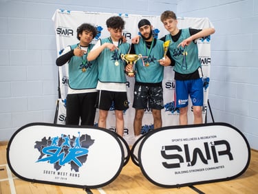 A winning youth basketball team posing with a gold trophy and medals at an SWR sports event.
