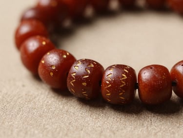 Close detail shot of a sacred hand-beaded object resting on a neutral warm cloth surface, intricate bead pattern with deep reds and golds, warm natural side-light, no distractions, shallow focus on bead texture