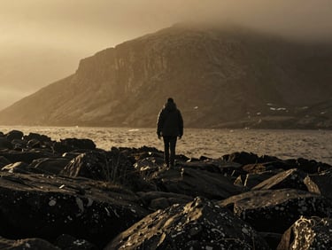 Cinematic 16:9 still of a solitary figure walking along a misty, rocky Scottish coastline, high-contrast black and white, dramatic low-key lighting