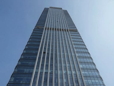 Symmetrical low angle shot of a modern commercial glass tower in Bengaluru, clear blue sky.
