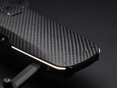 Macro detail of MEDIC-E1 drone's medical payload bay, carbon fiber, sharp edge-lighting, dark obsidian background.