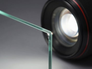 Close-up of a low-iron glass panel edge under bright studio strobe, showing true optical clarity with no green tint at the cut edge, 3/8-inch thickness visible