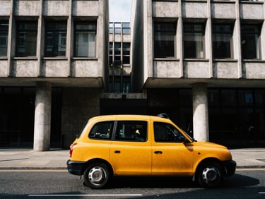 Candid motion shot of a yellow cab speeding past brutalist concrete buildings in London, high-contrast natural light