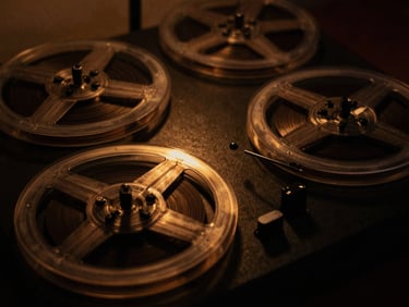 Close-up of a vintage tape machine's spinning reels, glowing amber lights, deep shadows, 35mm film grain, moody analog photography.