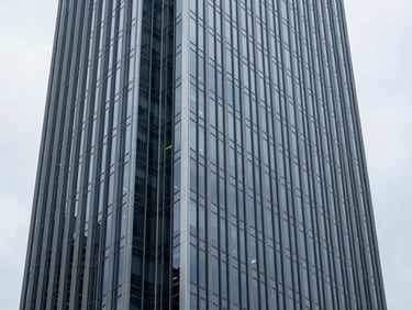 Architectural wide shot of a modern office tower facade in Brisbane, crisp overcast daylight, steel blue reflections, premium editorial style