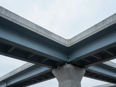 Architectural low-angle shot of an engineered concrete highway bridge, clean structural lines, cool overcast daylight.