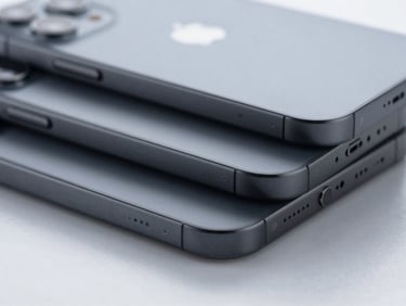 Crisp macro studio shot of sleek dark grey iPhone devices stacked neatly on a reflective surface, cool clinical lighting