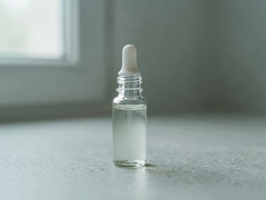 A small glass droplet bottle on a clean stone surface, soft diffused light, muted sage green background