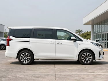 Three-quarter profile of a spotless white Tempo Traveller parked in a professional corporate lot under bright daylight.
