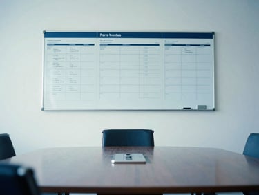 Crisp editorial photo of a clean corporate boardroom in Paris with a visible planning board on the wall, bright daylight, cool blue tones, 35mm