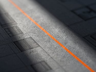 Extreme macro detail of a sharp slate gray architectural blueprint with a single safety-orange line, high-contrast directional natural light.