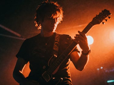 Tight close-up of a punk guitarist mid-performance, electric orange backlighting, motion blur, gritty 35mm film.