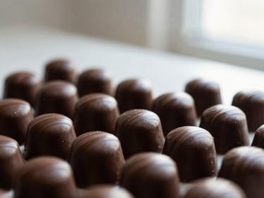 Close-up of perfectly tempered chocolate bonbons, glossy finish reflecting soft natural light, minimalist background, elegant editorial photography.
